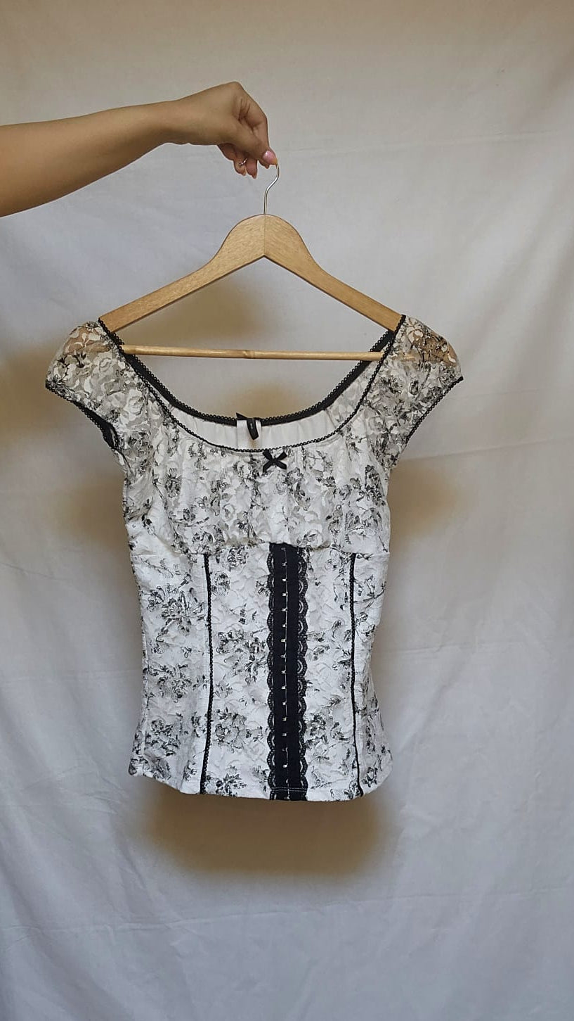 Floral-patterned top with black accents on a hanger against a white background