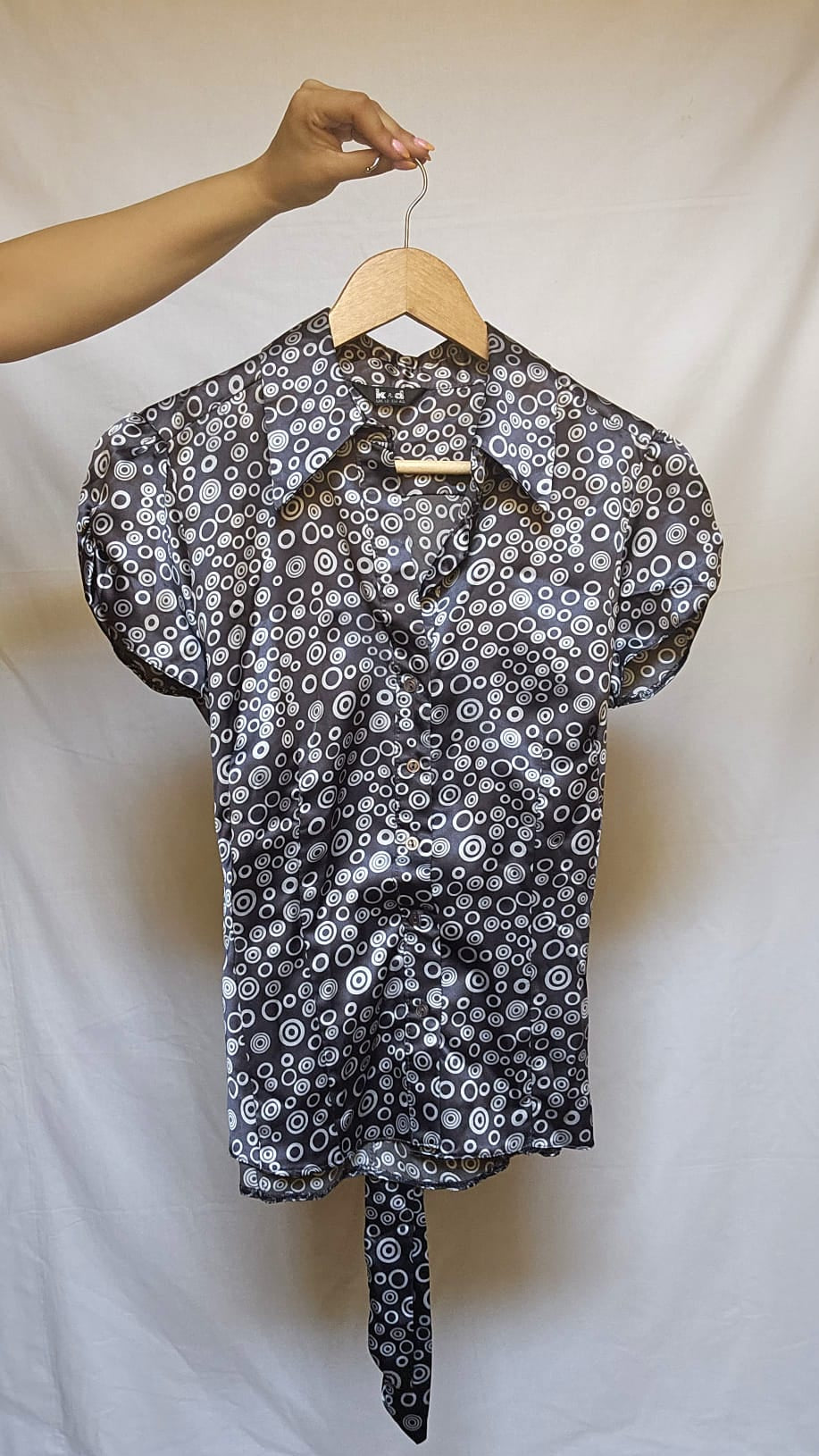 Black and white patterned blouse on a hanger against a plain background
