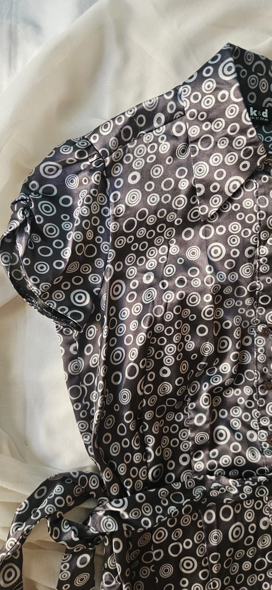 Black and white patterned top with a tie, on a light background
