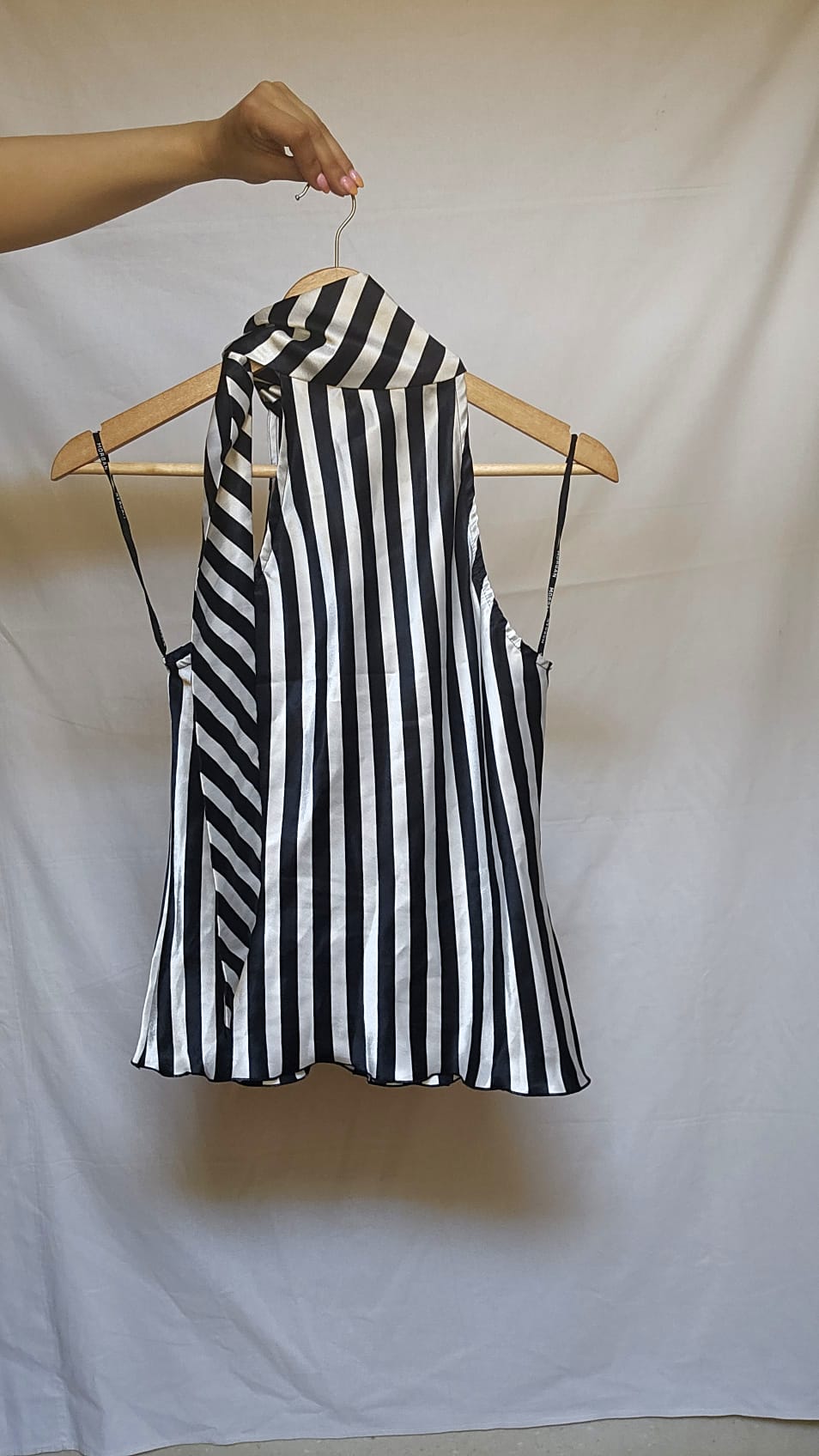 Black and white striped sleeveless top on a hanger against a plain background