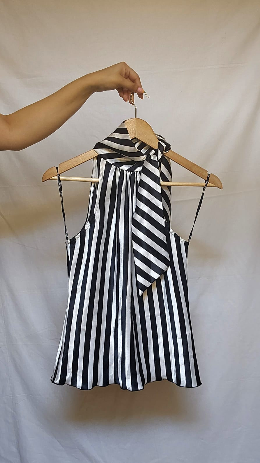 Black and white striped top on a hanger against a plain background