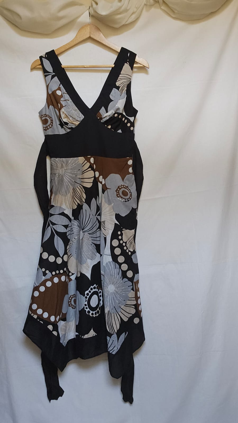 Black dress with floral patterns on a hanger against a white background