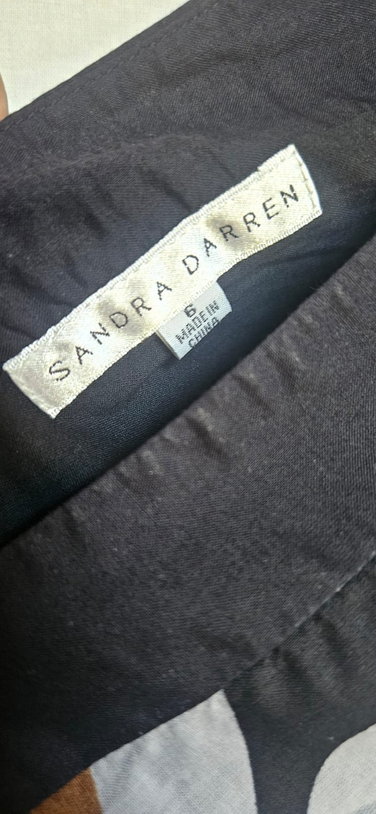 Label with 'Sandra Darren' branding on a dark fabric background