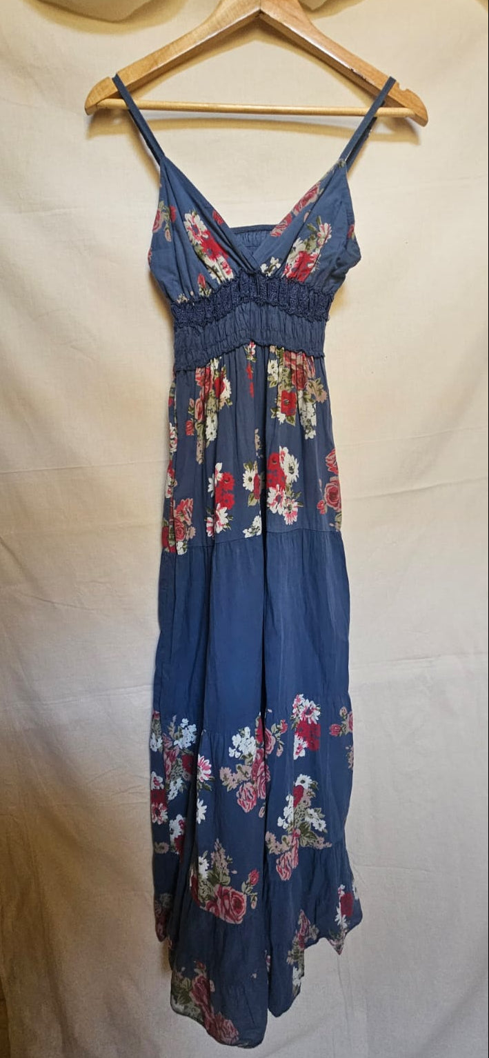 Blue floral dress hanging on a wooden hanger against a white background