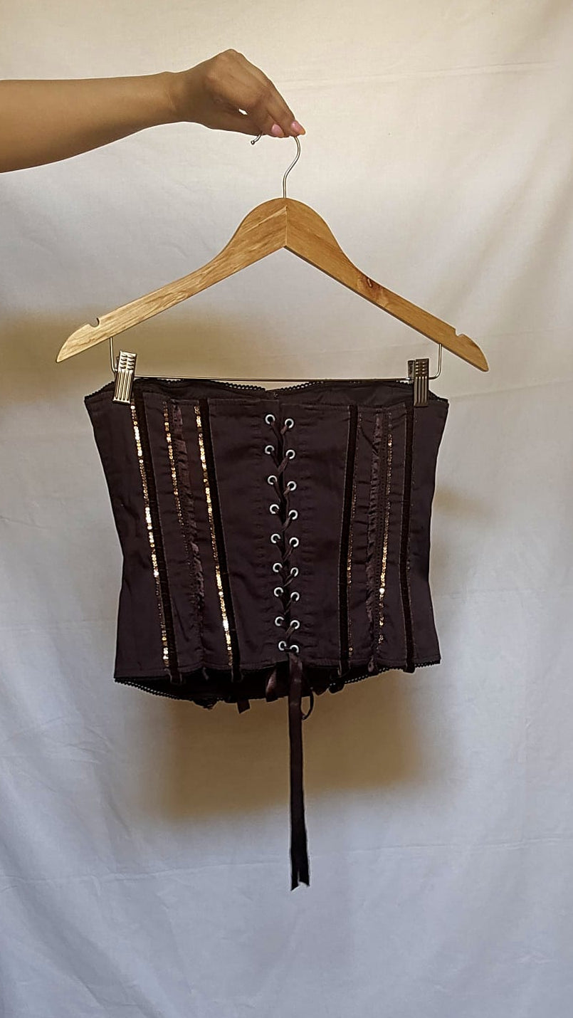 Brown corset on a hanger against a plain white background