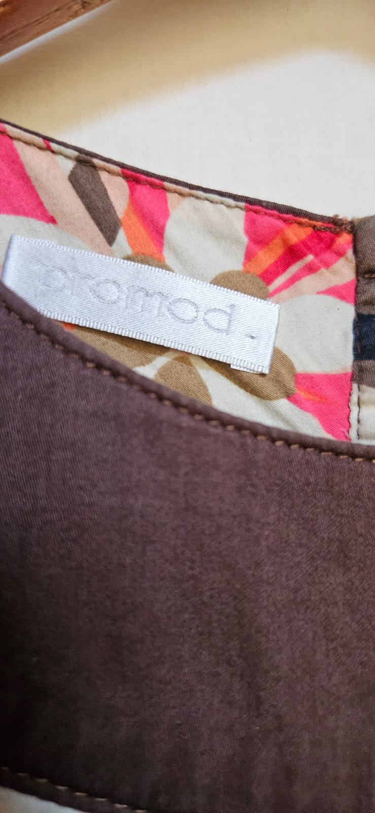 Close-up of a label on a brown fabric item with a colorful patterned background.