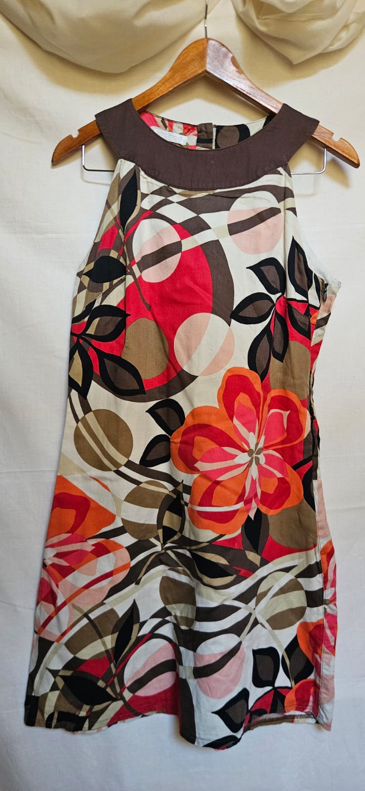 Colorful floral dress on a wooden hanger against a white background