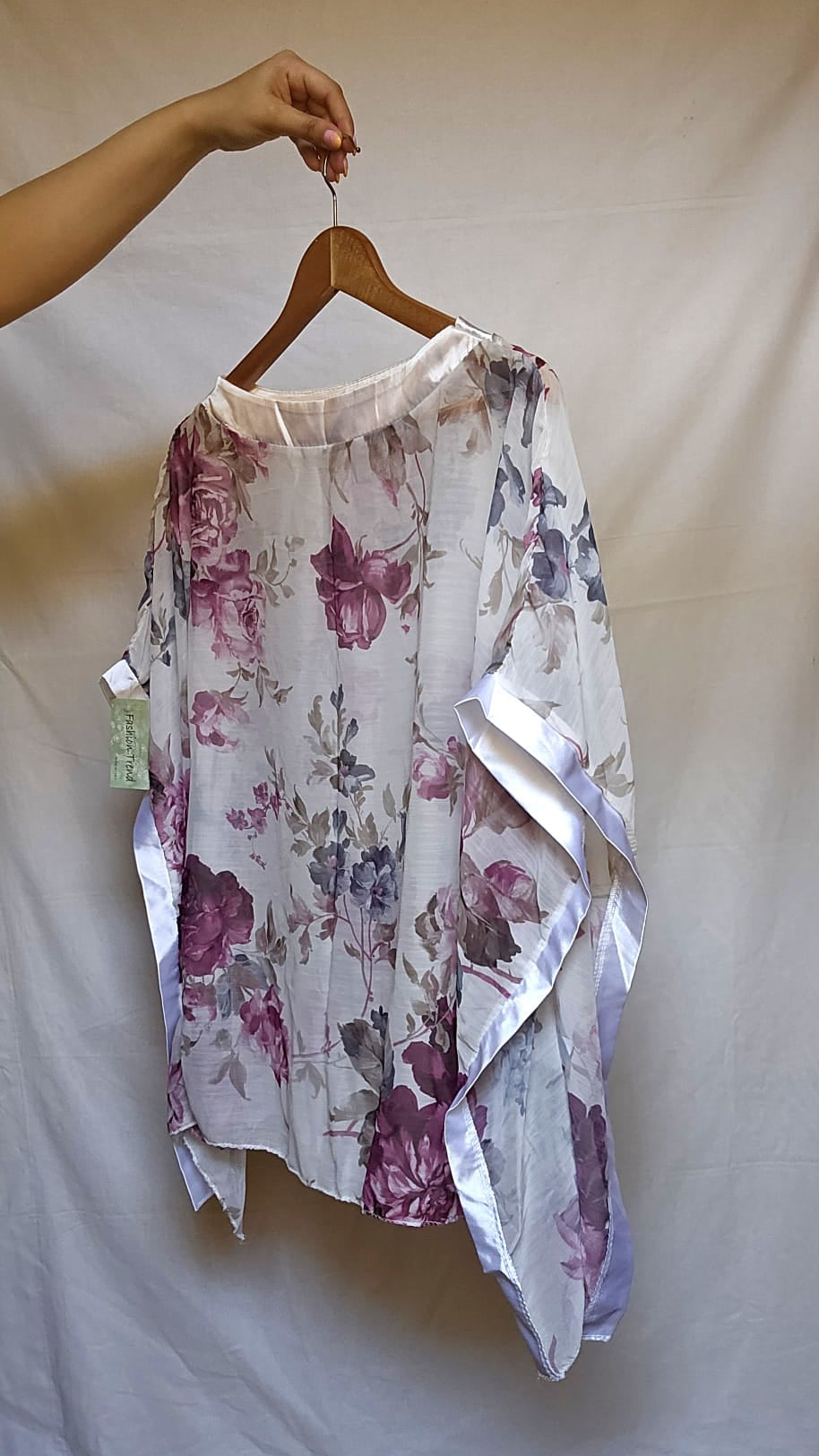 Floral blouse on a hanger against a plain background