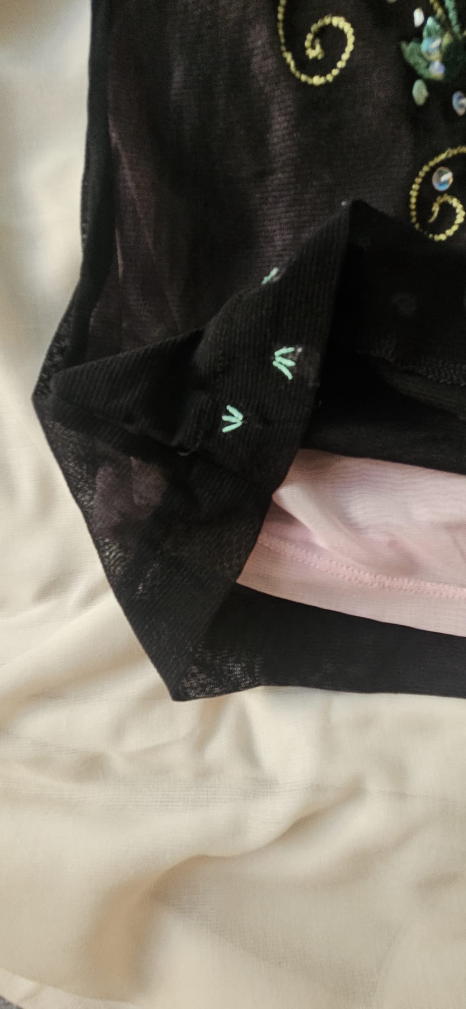 Close-up of a black garment with intricate embroidery on a beige background