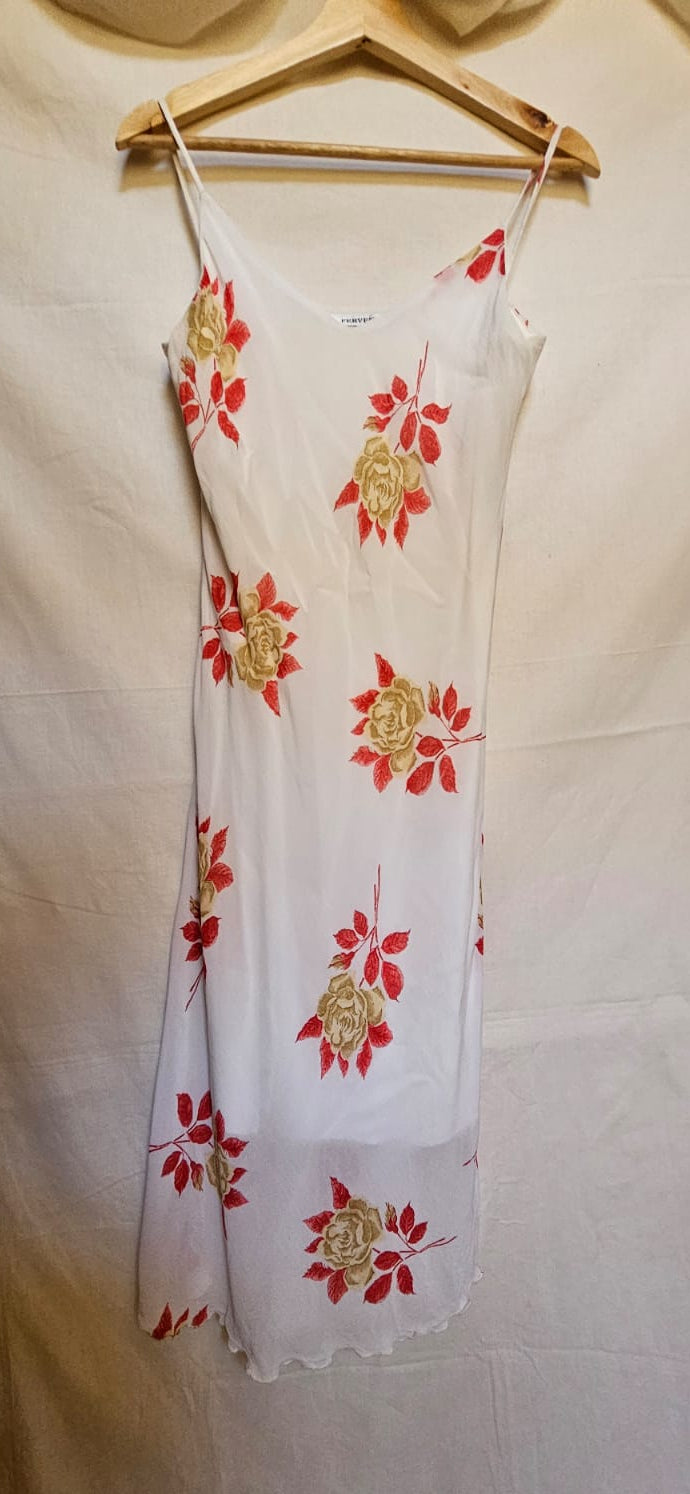 White dress with red floral patterns hanging on a wooden hanger against a white background