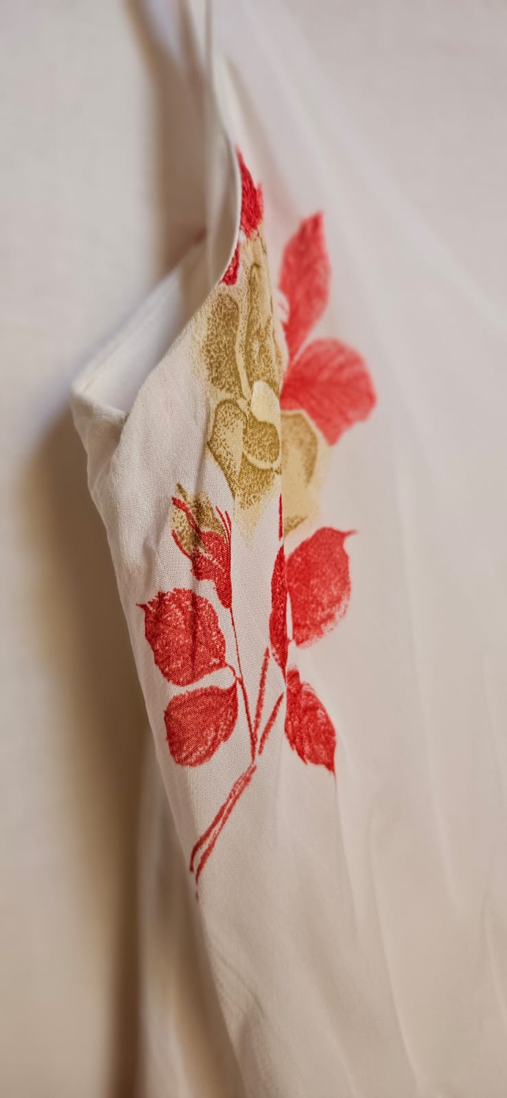 Close-up of a white dress with red floral patterns on a light background