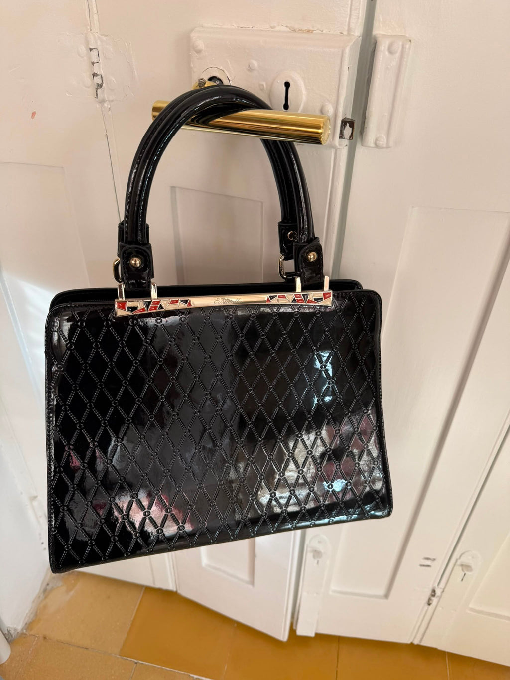 Black patent leather quilted handbag rear view with zip pocket