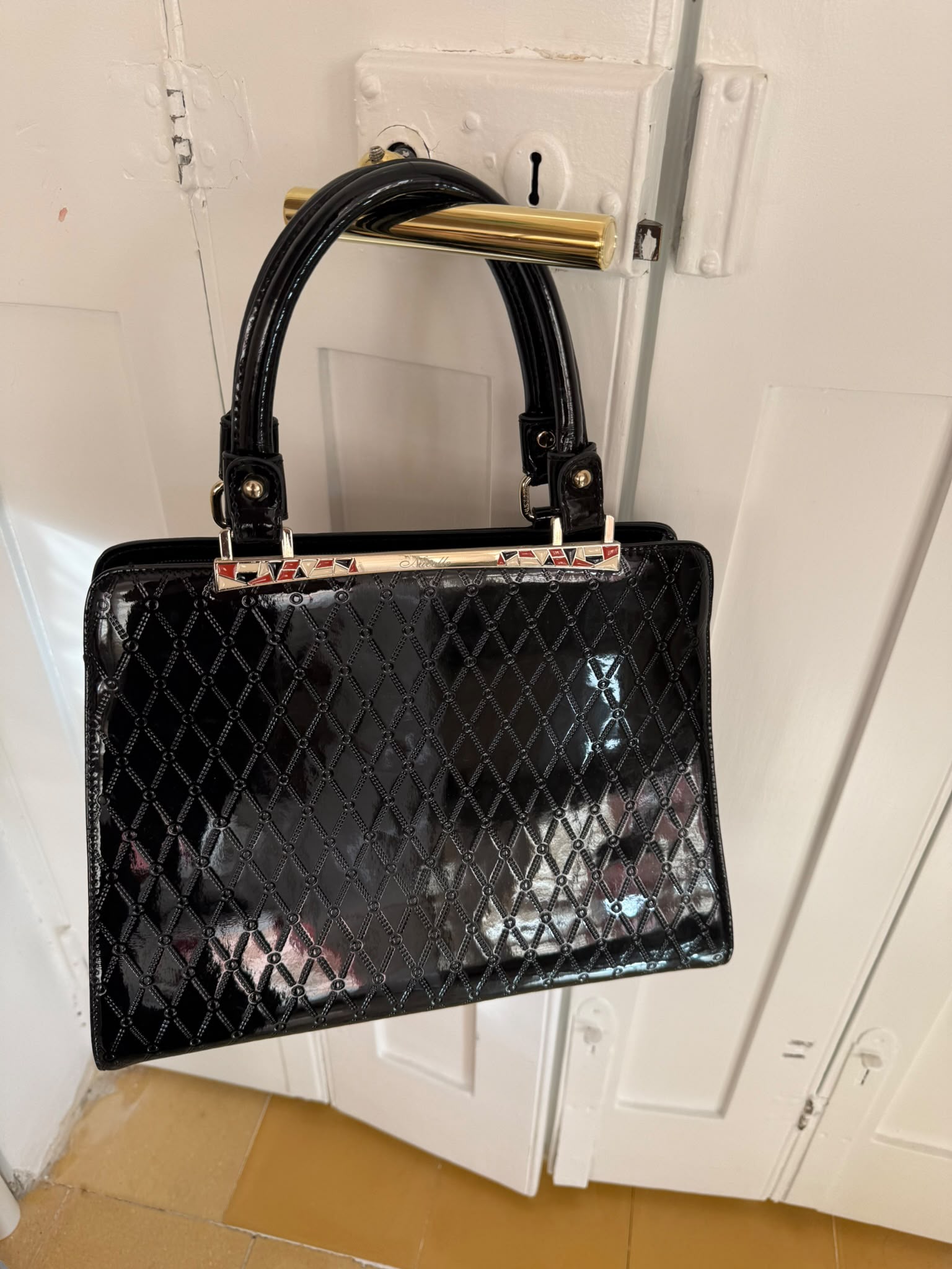 Black patent leather quilted handbag rear view with zip pocket