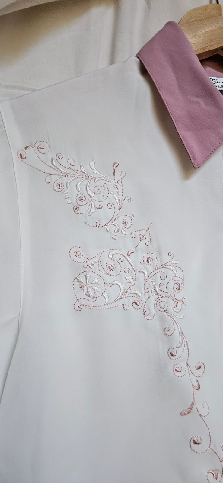 Floral scroll embroidery detail close-up on white blouse