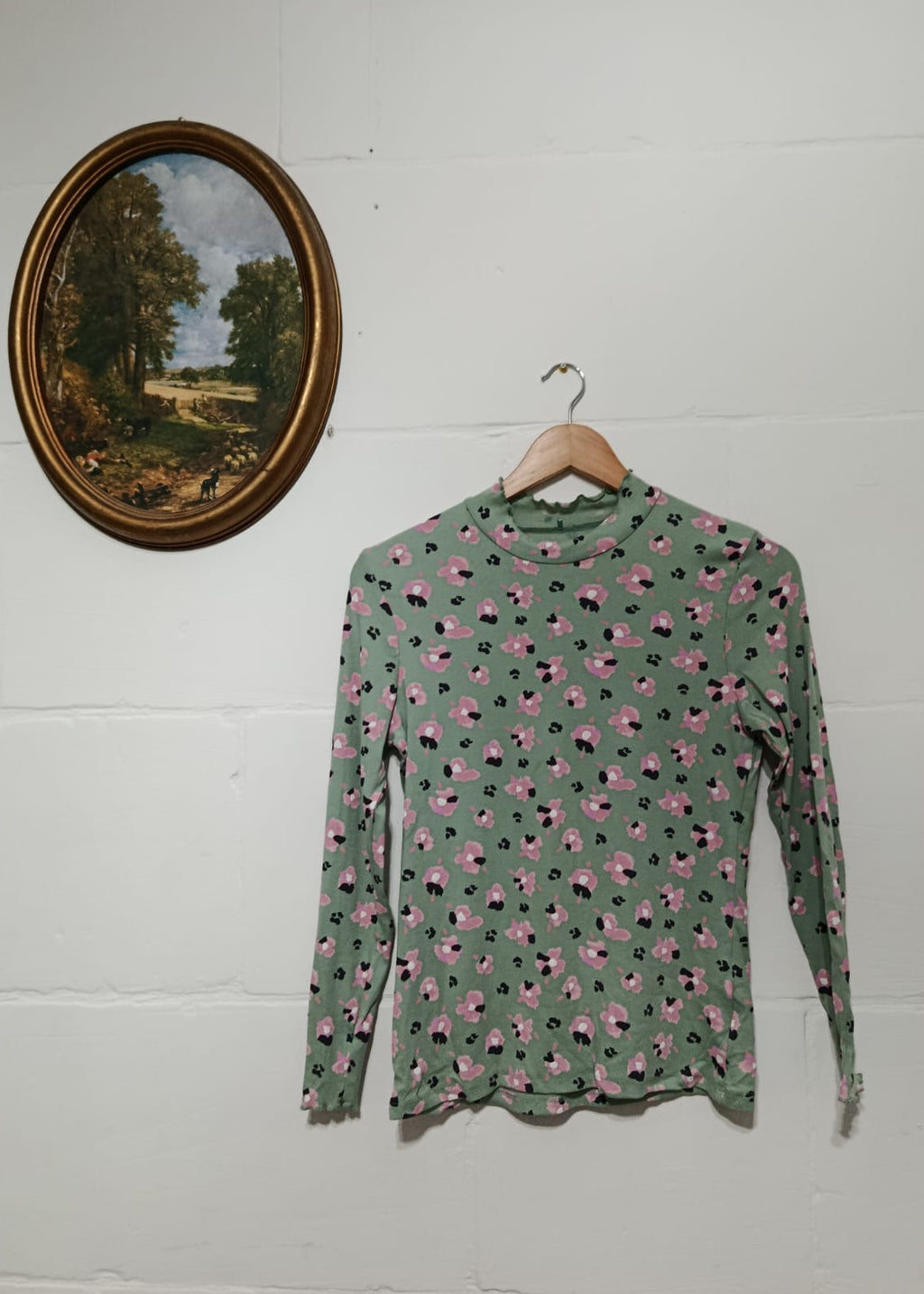 Full view of a sage green long-sleeve top with pink and black floral print