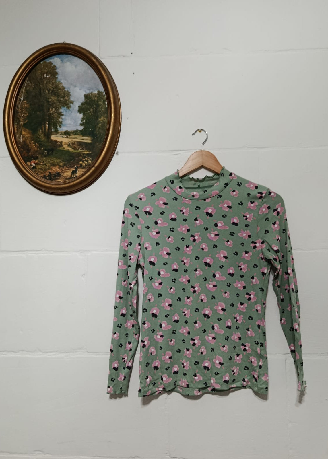 Full view of a sage green long-sleeve top with pink and black floral print