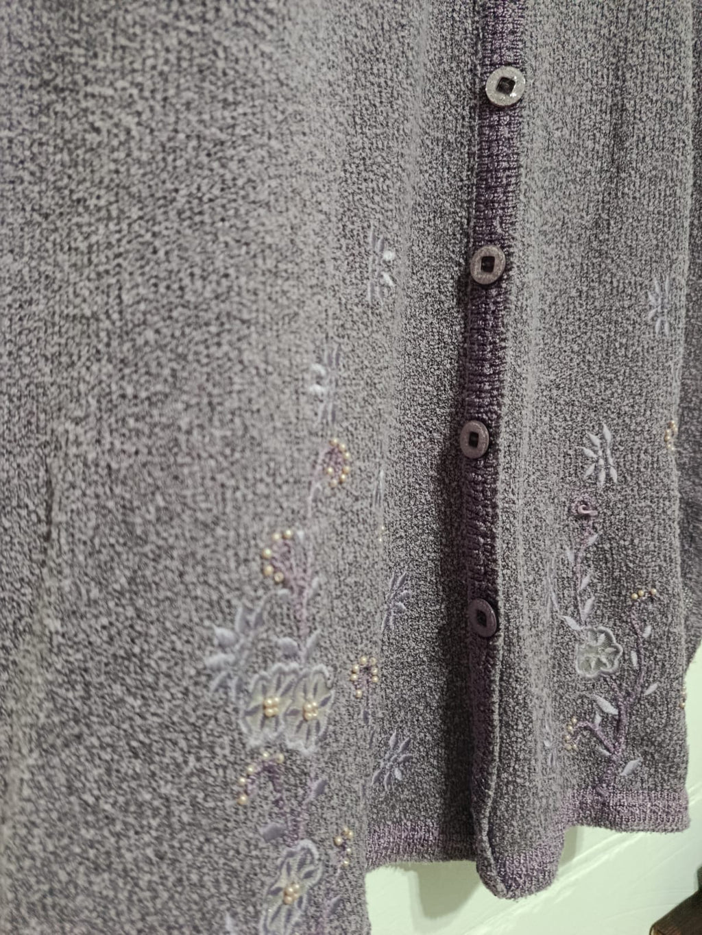 Close-up of floral embroidery and button front on a vintage lilac-purple La Dore cardigan