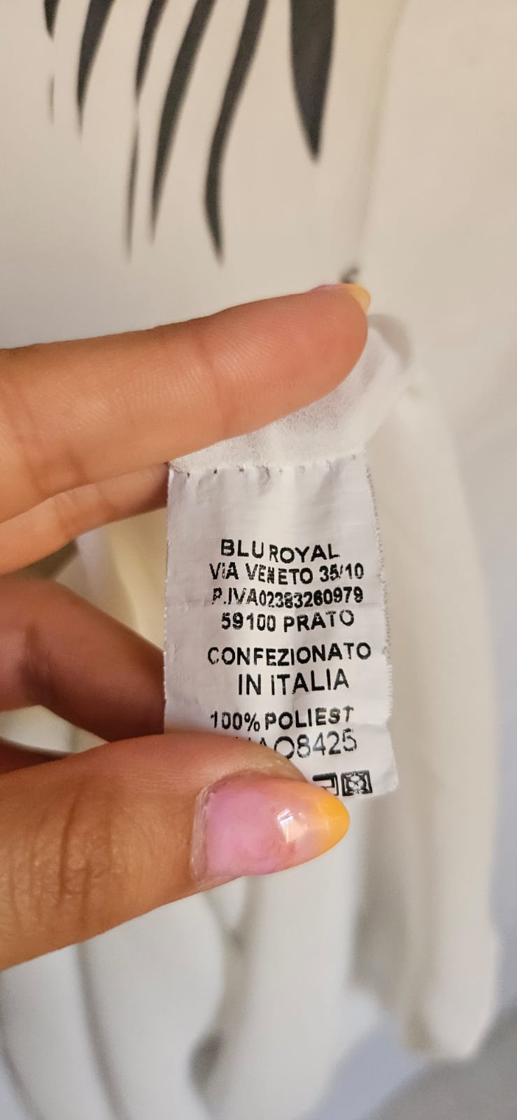Close-up of a clothing label held by a hand with a blurred background
