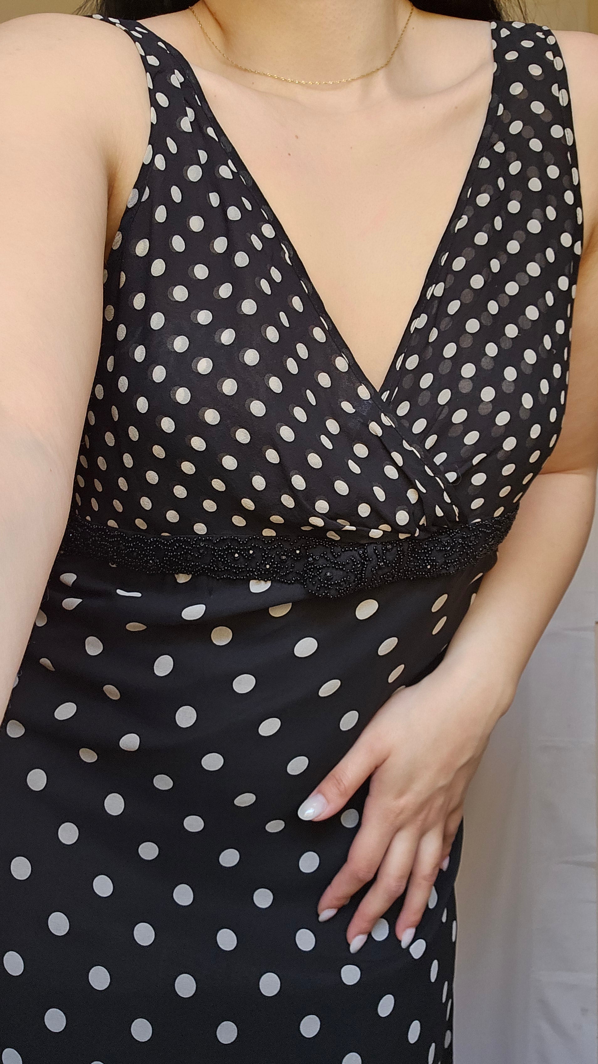 Black polka dot dress with cut-out design on a neutral background
